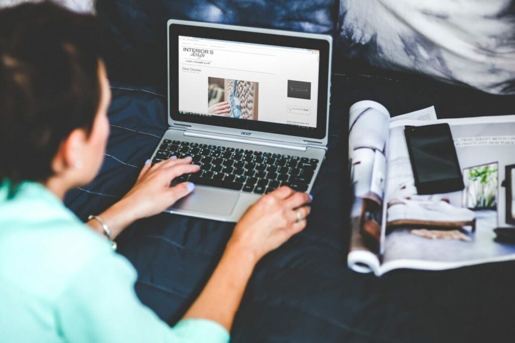 Woman typing on her laptop placed on her bed