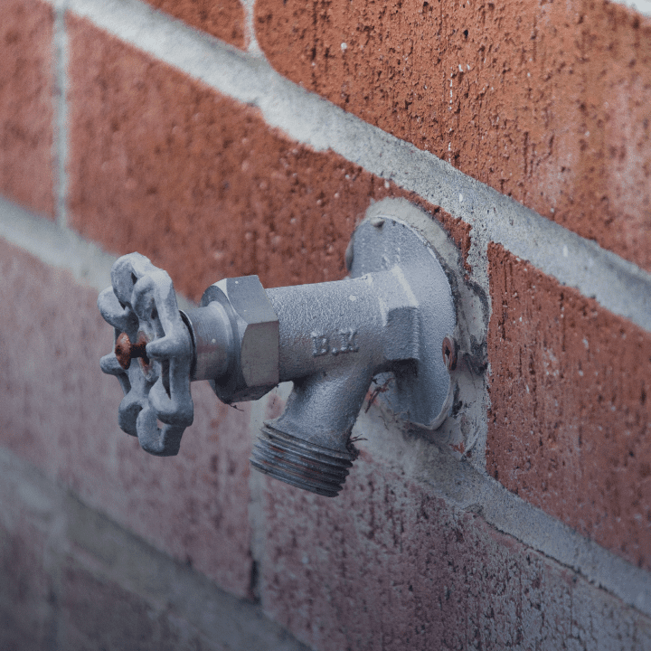 An exterior faucet mounted to a brick wall