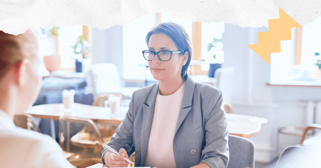 A person holding a pen and sitting across a desk from another person during a tenant screening interview.