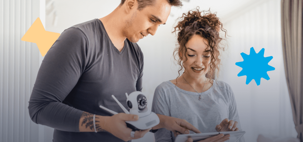 A couple is holding a security camera and tablet to prevent rental property vandalism.