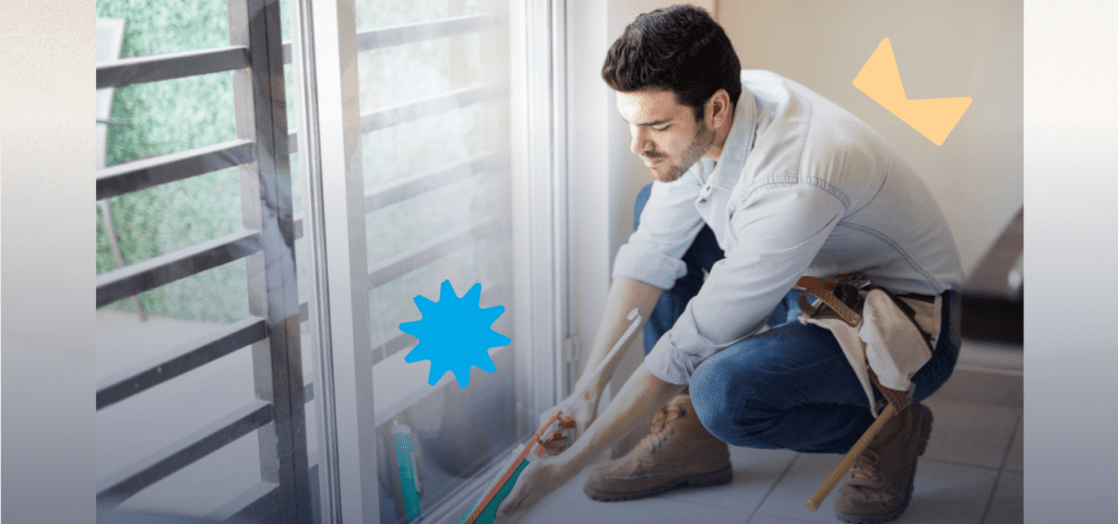 A person using a sealing gun to seal a glass door frame on a house to protect against flood risks.