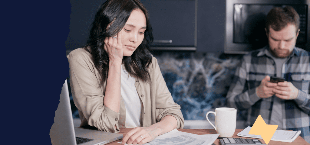 A person sitting and studying a piece of paper at their desk, resting their face against their hand.